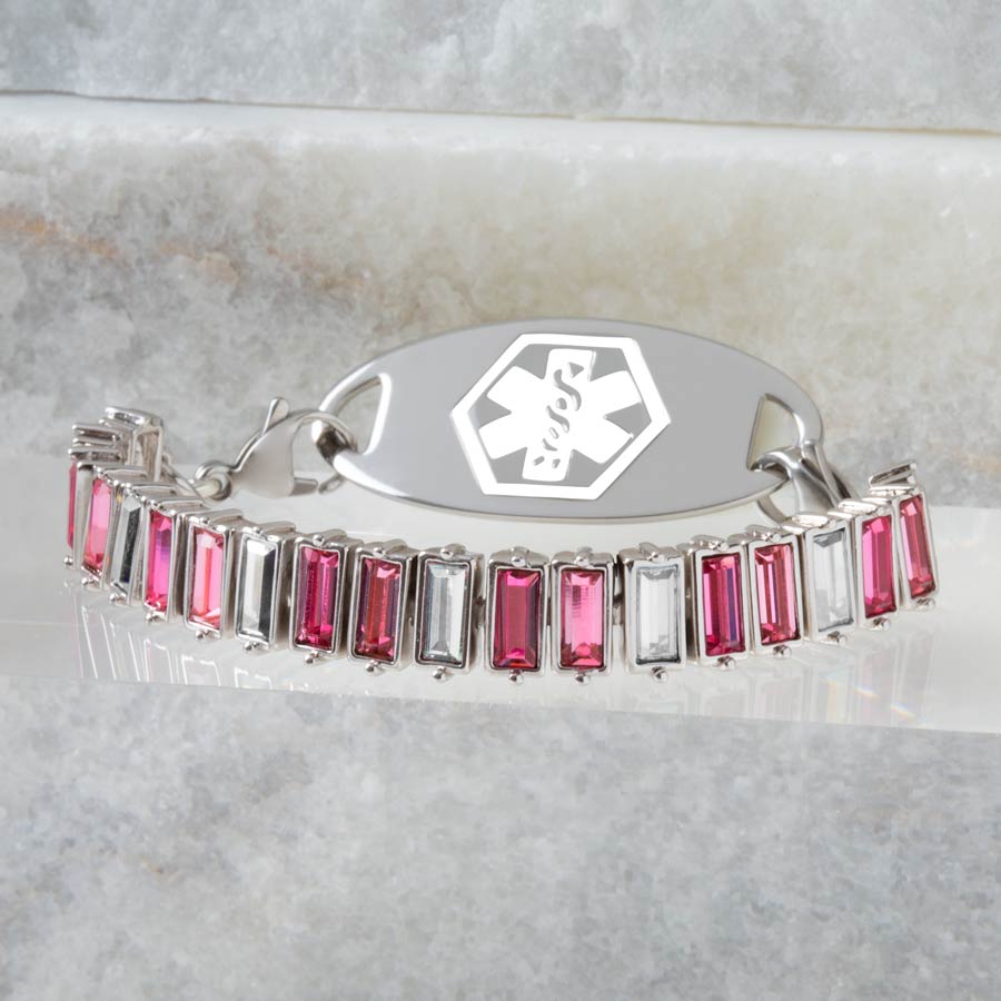 Crystal medical ID bracelet with varying shades of pink and magenta on a stone background