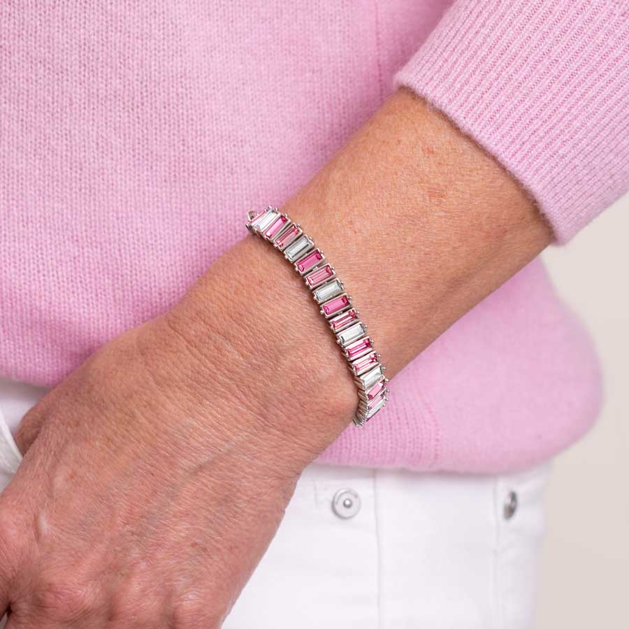 Woman in pink sweater wearing hot pink, magenta, blush, and clear baguette cubic zirconia crystal silver tone medical ID bracelet.