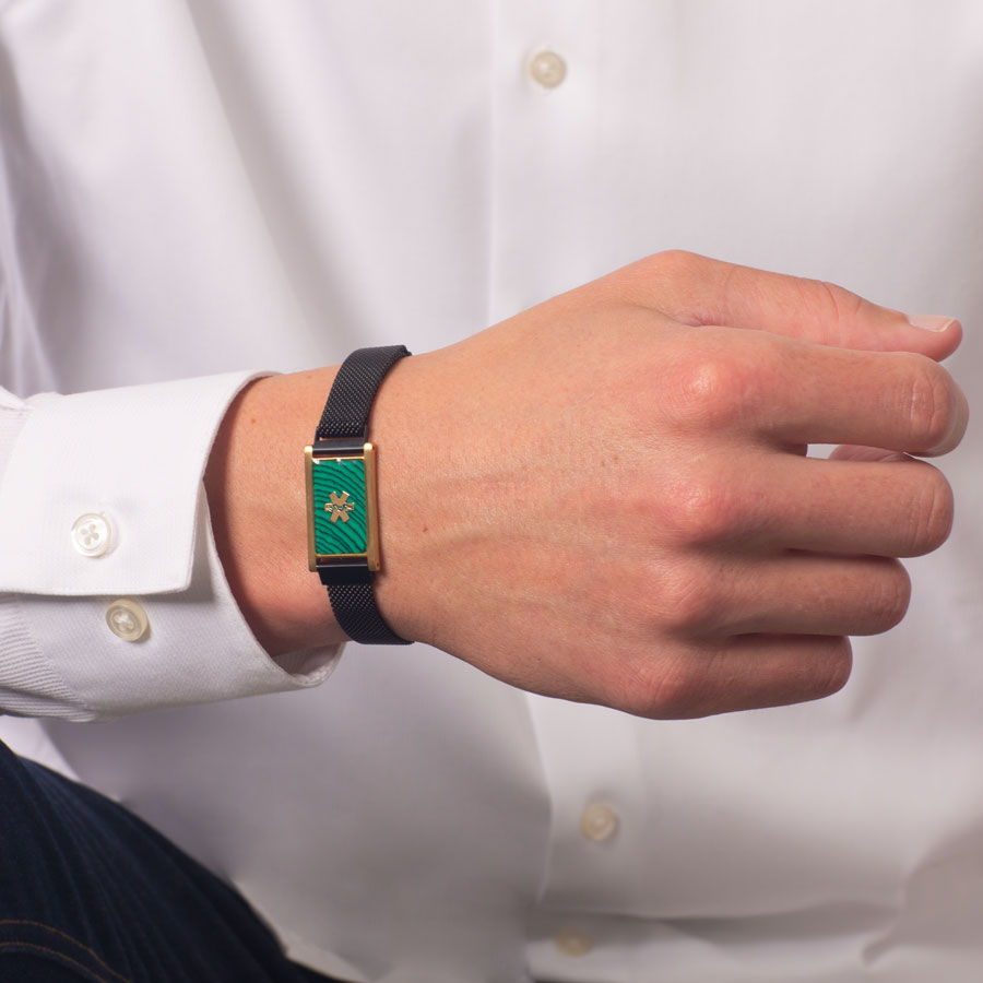 Man wearing black stainless steel mesh band affixed to gold tone stainless steel medical ID tag with malachite inlay and gold tone medical symbol.