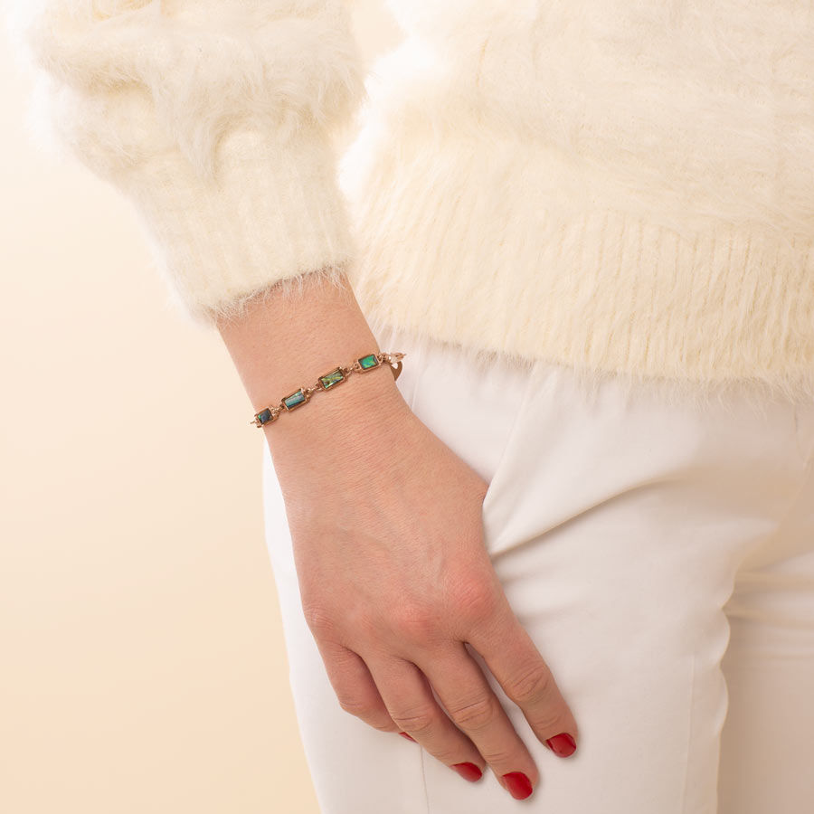 Woman with hand in pocket wearing abalone in blue and green with rose gold medical ID chain bracelet