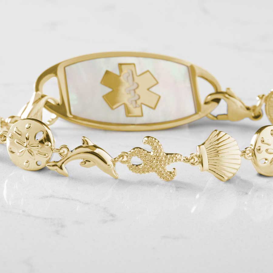 Delicate sea life charms detail on gold medical ID bracelet.