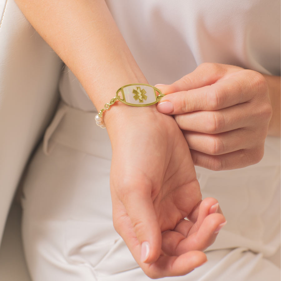 Woman showing gold tone stainless steel medical ID tag with gold tone medical caduceus.