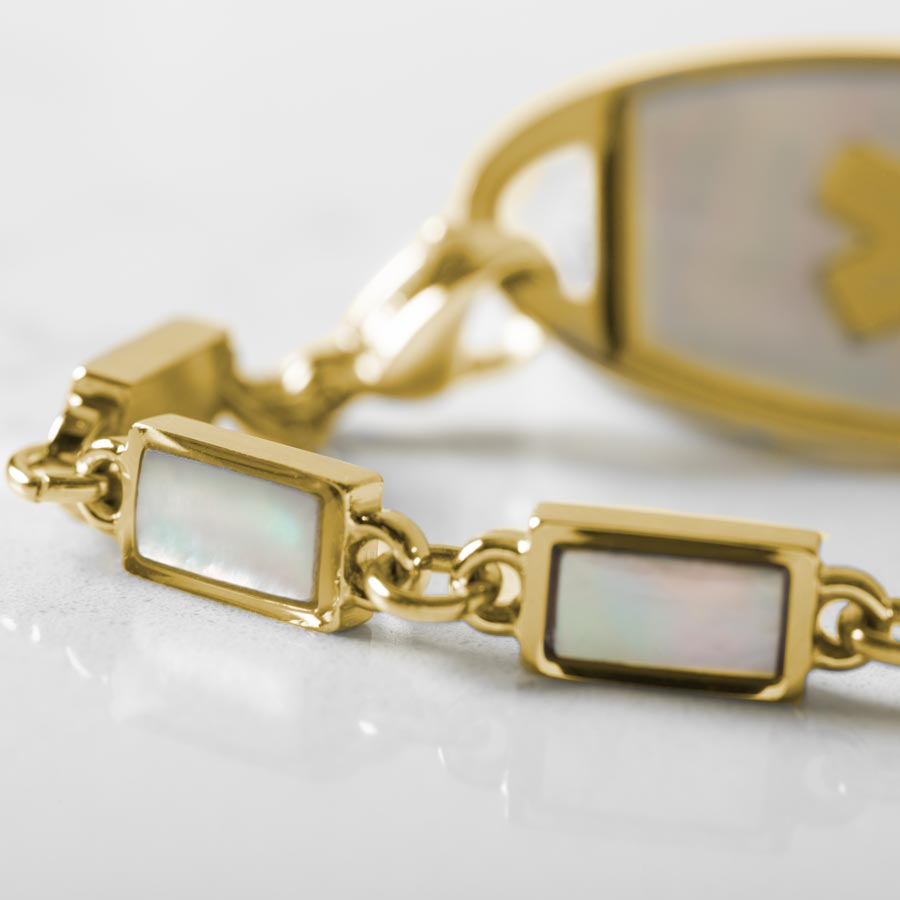 Up close image of yellow gold links and mother of pearl inlay and mother of pearl medical ID tag