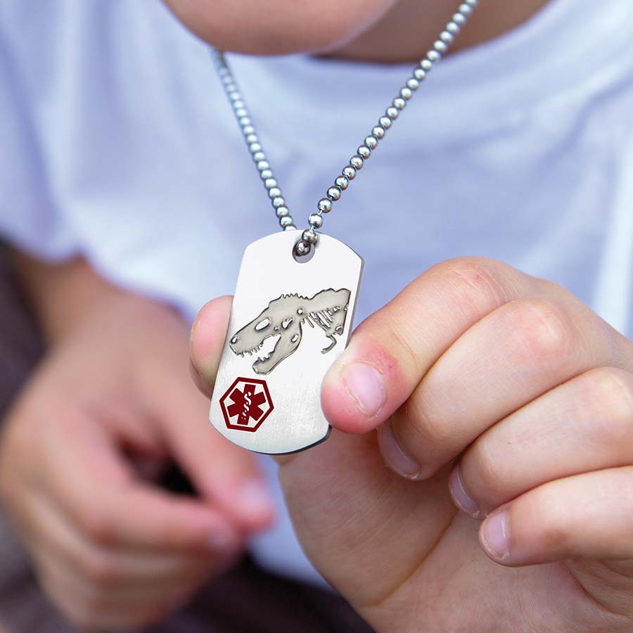 Boy wearing a Safe T Rex Medical ID Dog Tag, a stainless tag that features a roaring T-Rex and red caduceus, on a ball chain