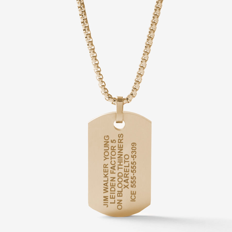 The back side of the gold tone medical ID dog tag necklace with black decorative inlay on a gold tone rolo chain showing engraving example.