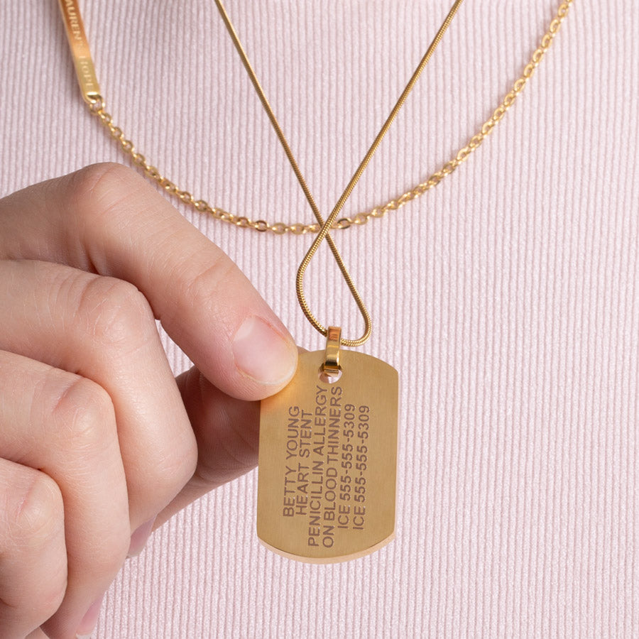 Woman showing custom laser engraved medical ID alert dog tag necklace in yellow gold