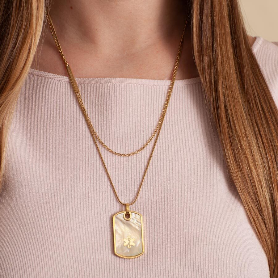 Woman wearing 14k gold medical ID dog tag with mother of pearl inlay on a gold tone chain