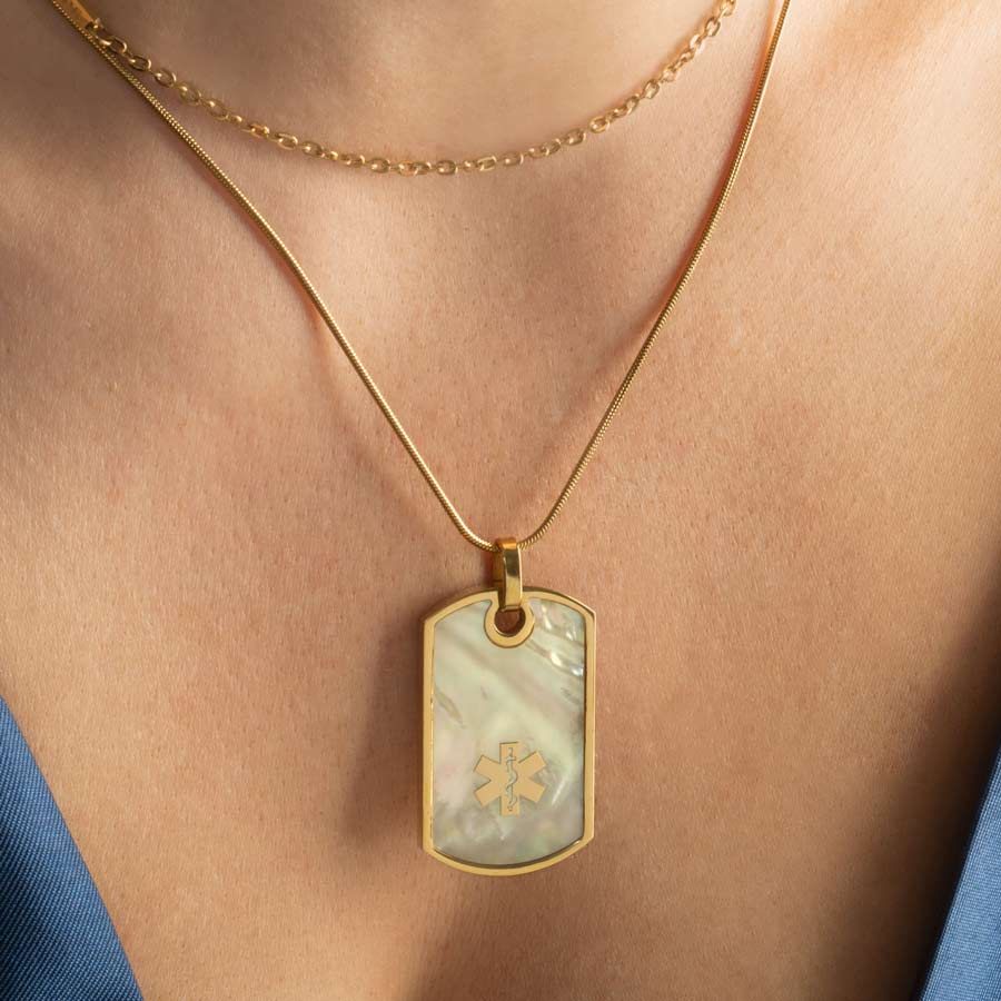 Woman wearing gold medical ID dog tag necklace with beautiful mother of pearl inlay