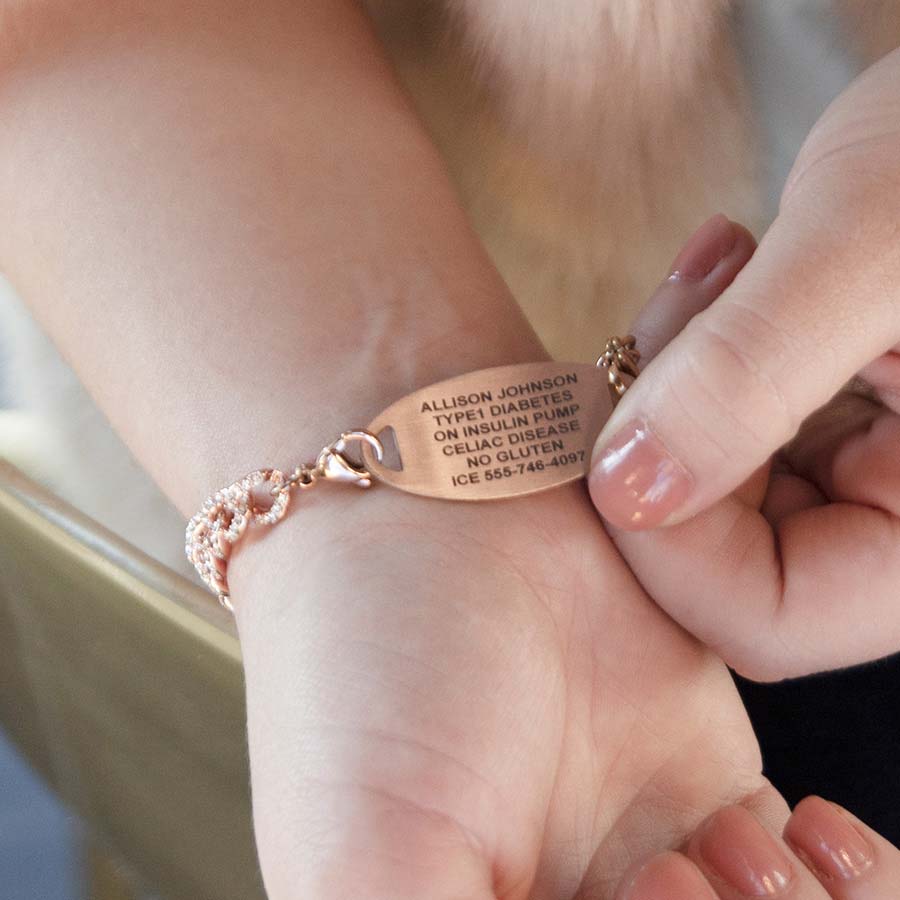 Woman showing custom laser engraved medical alert tag in rose gold