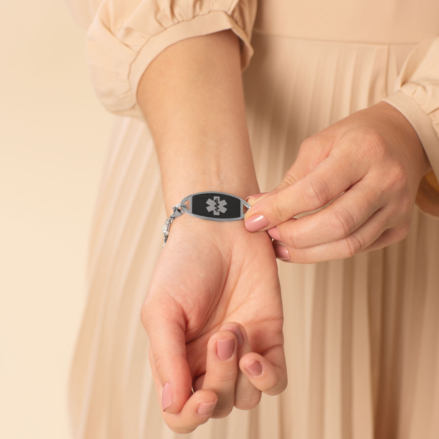 Woman showing decorative medical alert tag with red medical caduceus symbol