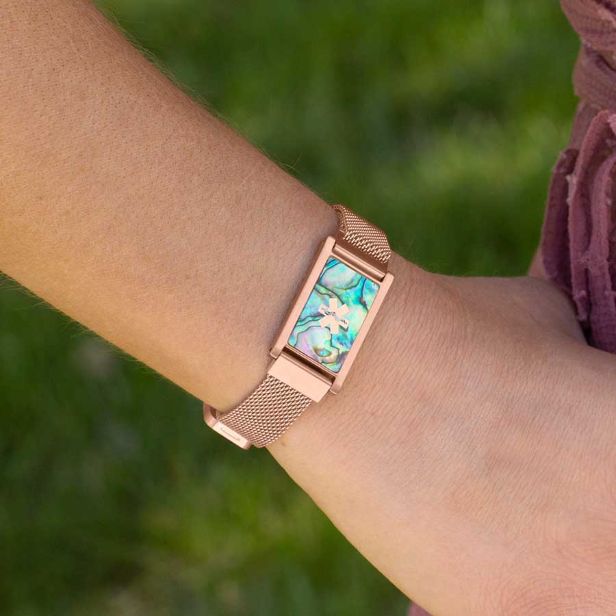 Woman wearing rose gold and abalone medical ID bracelet with mesh band and rose gold medical symbol