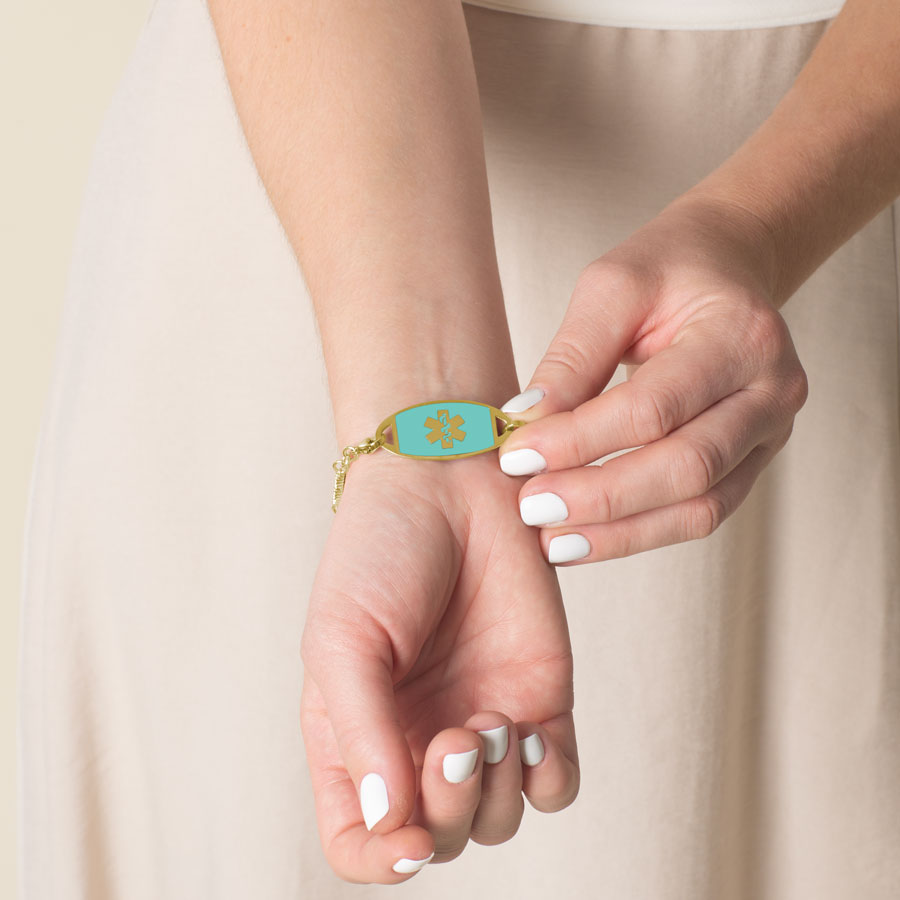 Model displaying her Gold medical ID tag, featuring a gold cadu and turquoise stone inlay.