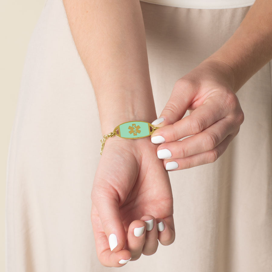 Woman showing mint medical ID tag with gold medical caduceus symbol