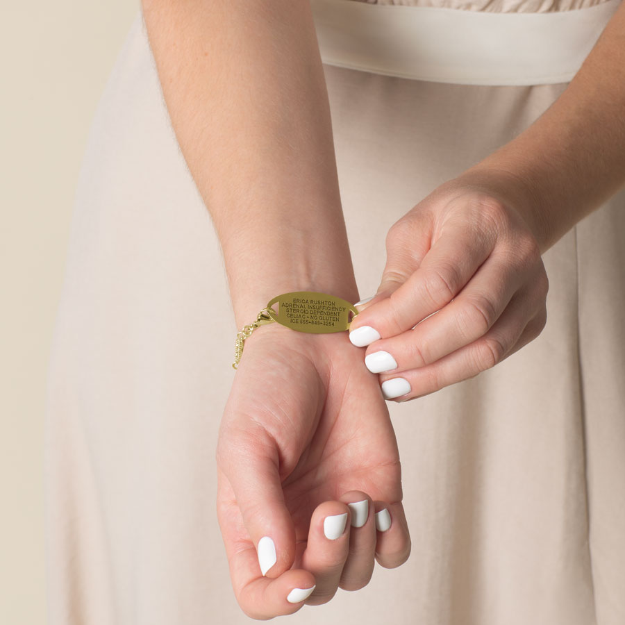 Woman showing custom premium laser engraving on gold tone stainless steel medical alert tag.