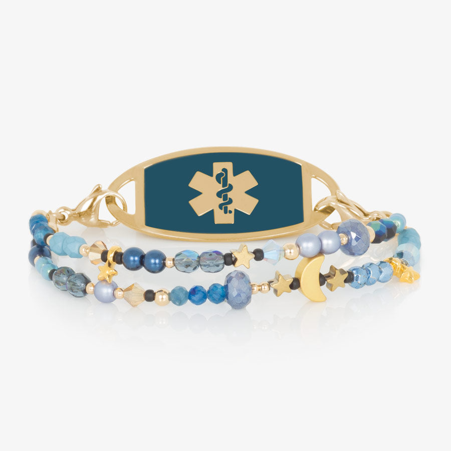 Navy, periwinkle and gold beaded medical ID bracelet with gold tone moon and star charms paired with gold tone stainless steel medical ID tag with sapphire blue paint inlay.