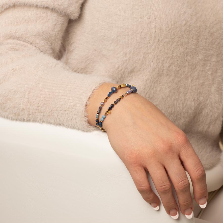 Woman wearing navy, periwinkle, and gold beaded medical ID bracelet with gold tone moon and star charms.