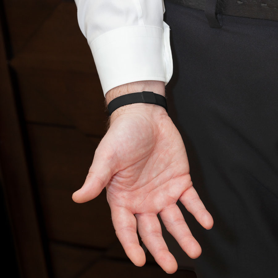 Man showing magnetic clasp on black stainless steel adjustable mesh band medical ID bracelet.