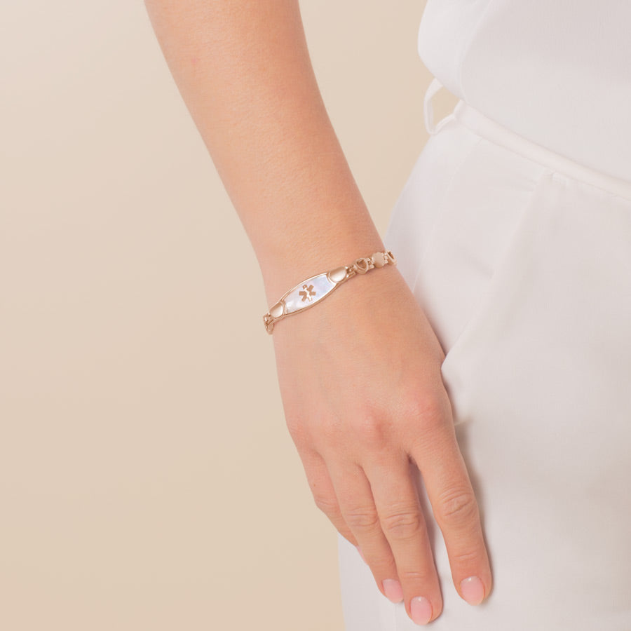 Woman wearing Mother of Pearl Love Links Medical ID Bracelet, plated stainless steel rose hearts and rose gold caduceus