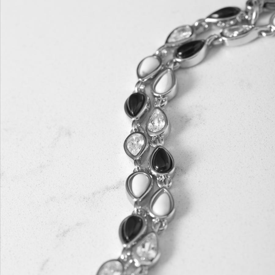 Close up image showing alternating teardrop links of black onyx, white howlite and clear cubic zirconia