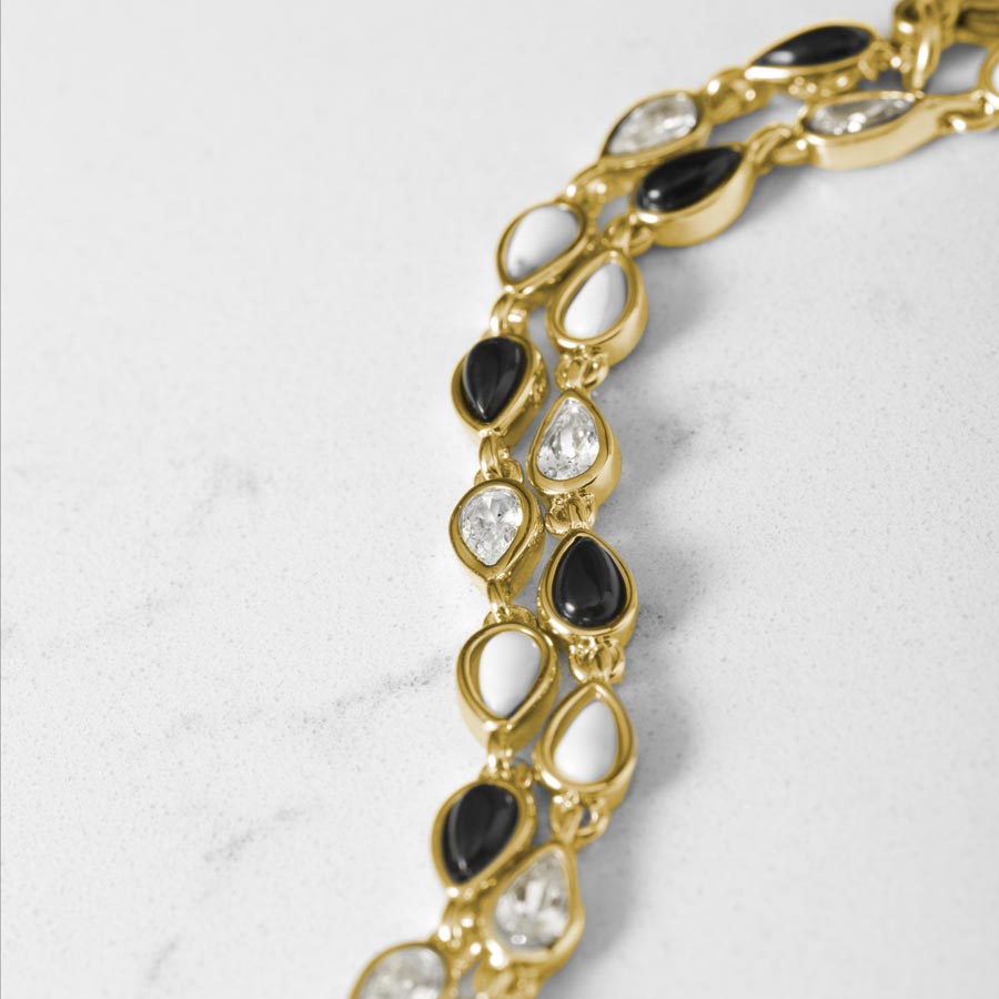 Close up image showing 12k gold plated alternating teardrop links of black onyx, white howlite and clear cubic zirconia