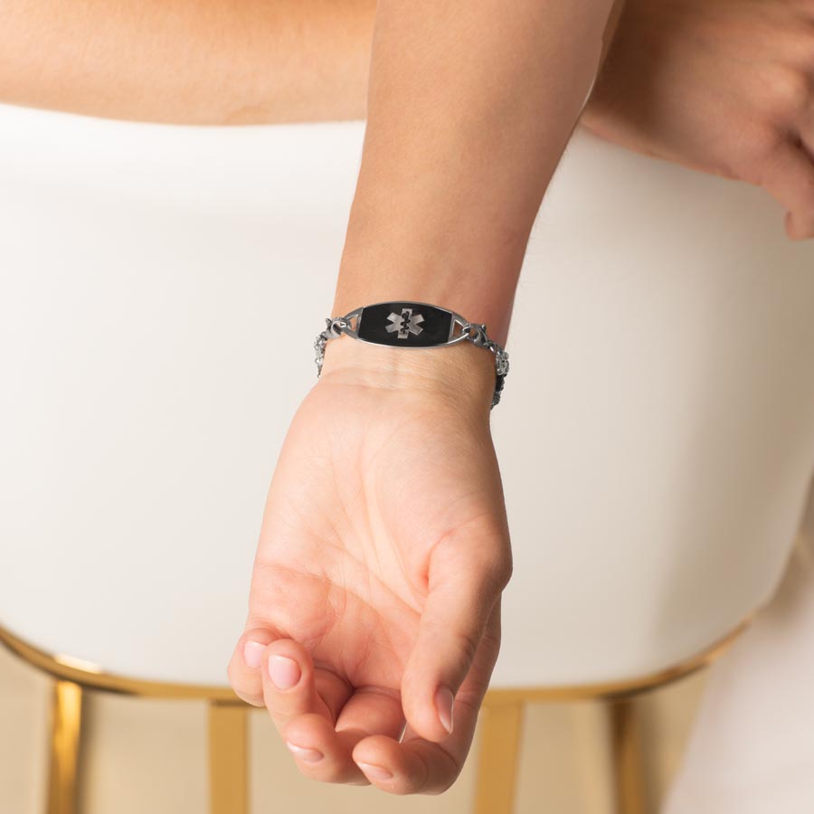 Woman showing stainless steel medical ID tag with black inlay and stainless steel medical ID symbol