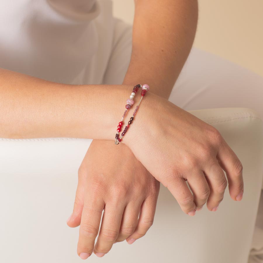 Woman with hands crossed wearing red and pink beaded medical ID bracelet