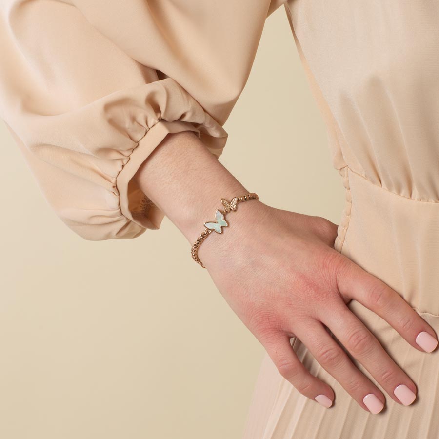 Woman wearing a rose gold tone box chain featuring a double butterfly centerpiece, inlaid with Mother of Pearl and cubic zirconia crystals.