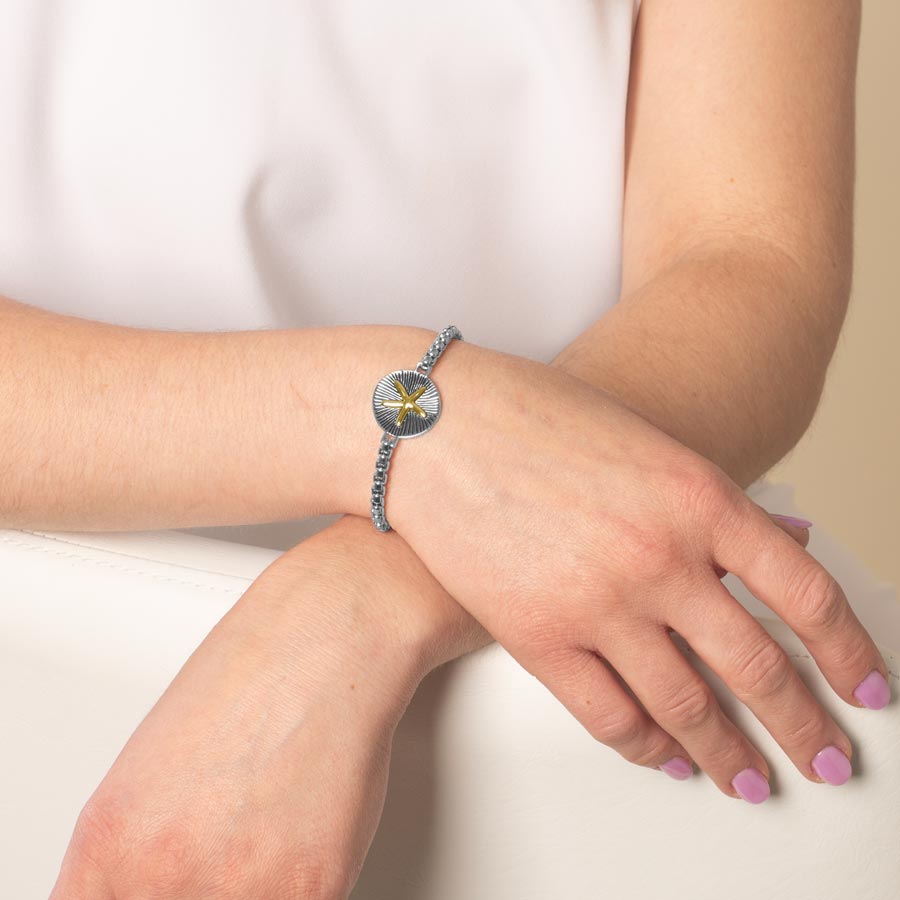 Woman wearing medical ID bracelet with gold and silver Sand Dollar centerpiece.