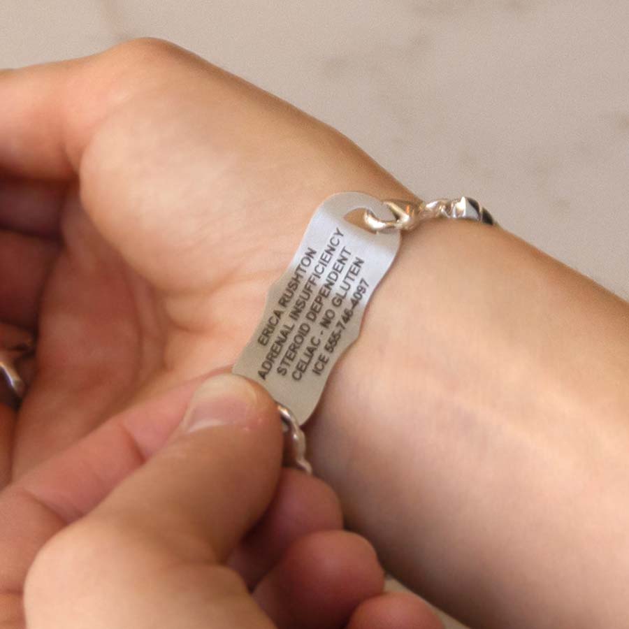 Woman showing custom engraved medical ID tag with dark laser engraving