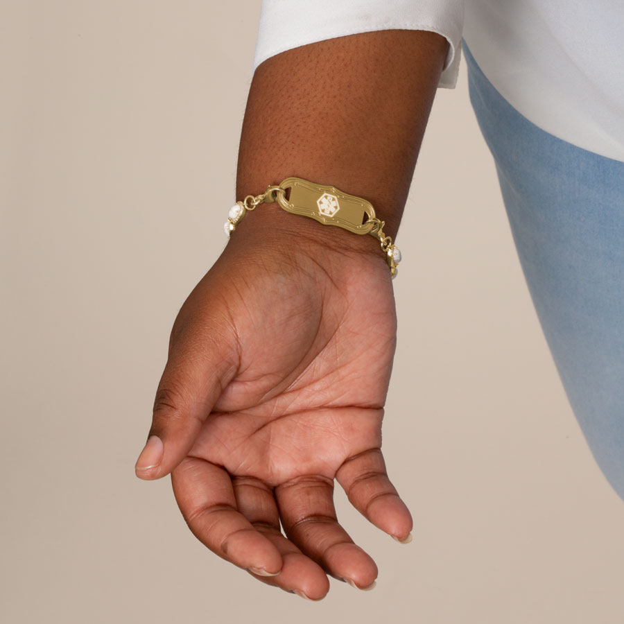 Woman showing gold tone stainless steel la petite medical ID tag with white medical caduceus symbol