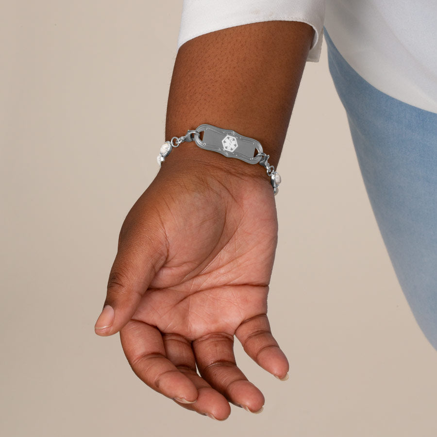 Woman wearing stainless steel medical ID tag with white medical symbol.