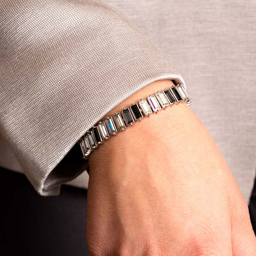 Woman in gray jacket wearing silver tone baguette med ID bracelet with black, clear, gray and iridescent crystals.