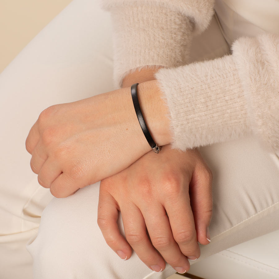 Woman wearing black leather medical alert bracelet.