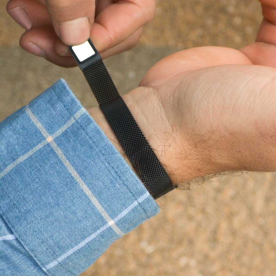 Man wearing black mesh magnetic medical ID bracelet with white caduceus showing magnetic clasp.