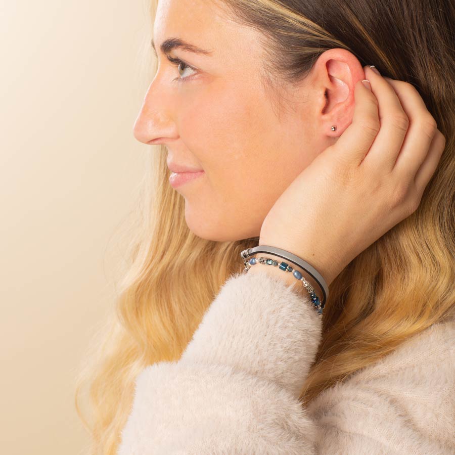 Woman with hand to face wearing blue beaded medical ID bracelet