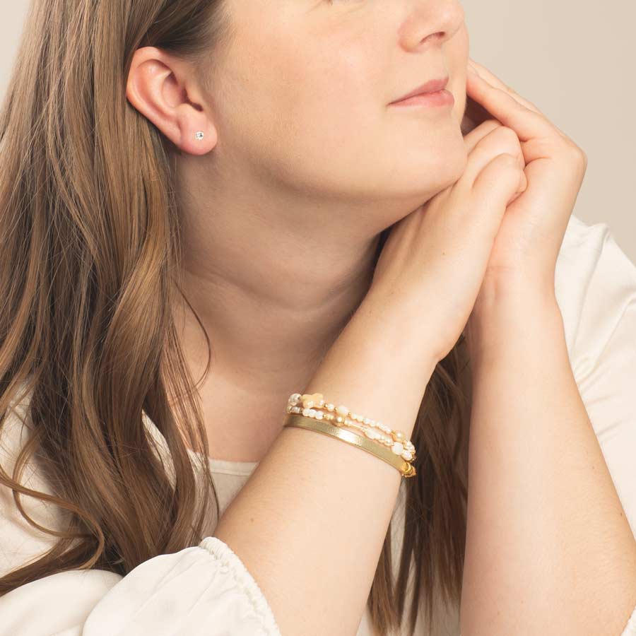 Woman Standing at counter wearing freshwater pearl and gold tone beaded med ID bracelet.