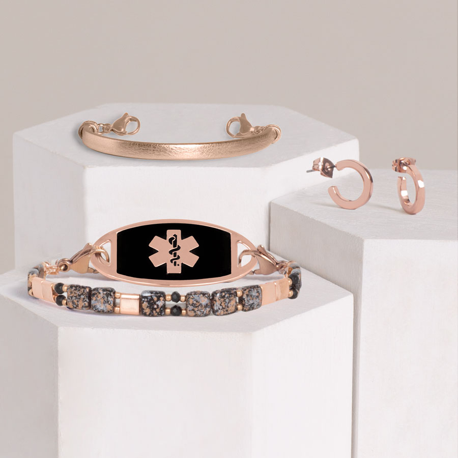 Black, rose gold, and crystal beaded stretch bracelet, rose tone leather bracelet, and rose gold tone hoop earrings on hexagon blocks.