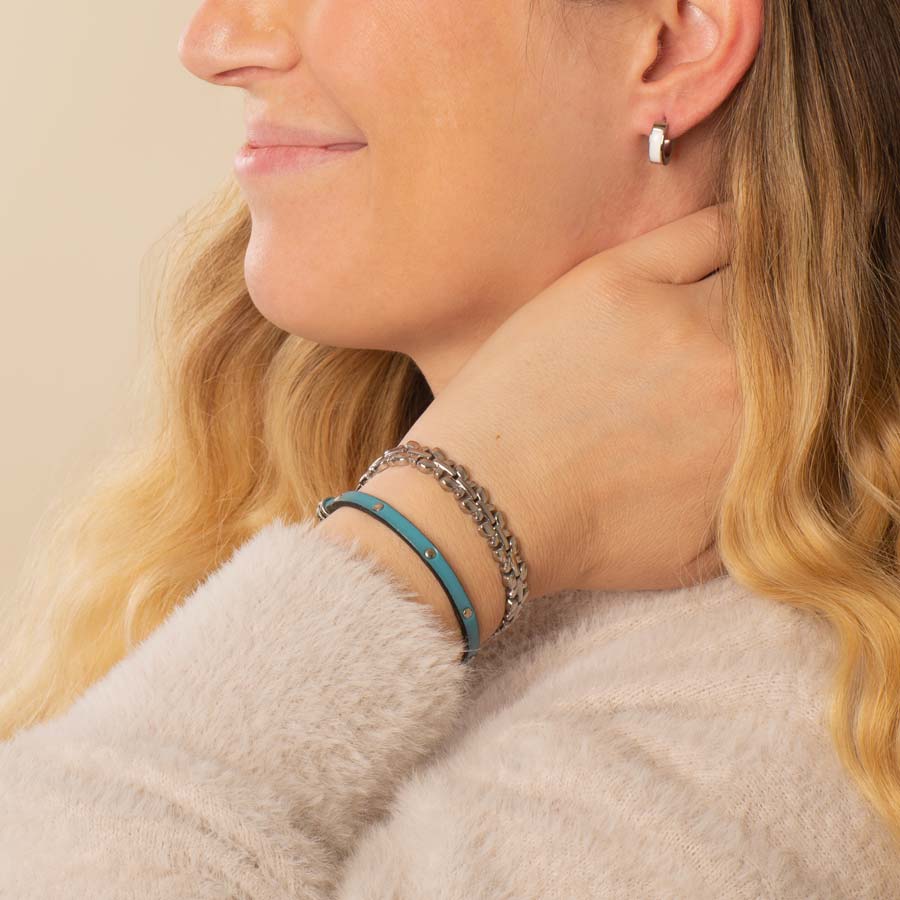 Woman wearing stainless steel chain and leather medical ID band with earrings