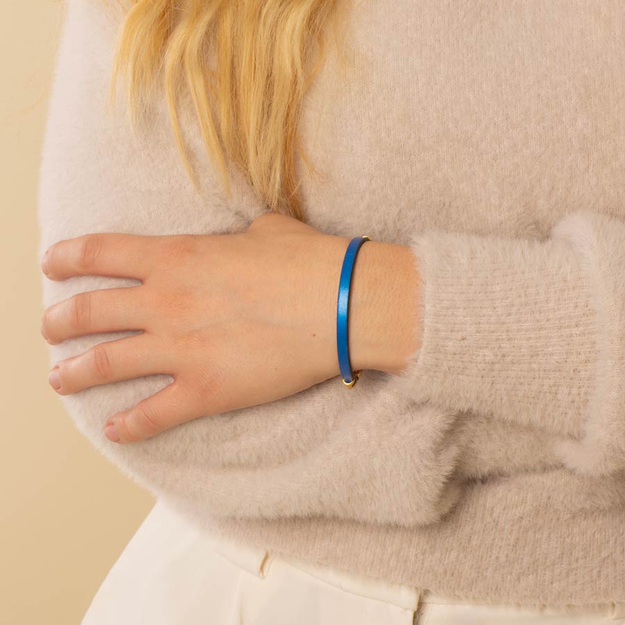 Woman wearing blue metallic leather medical ID bracelet.