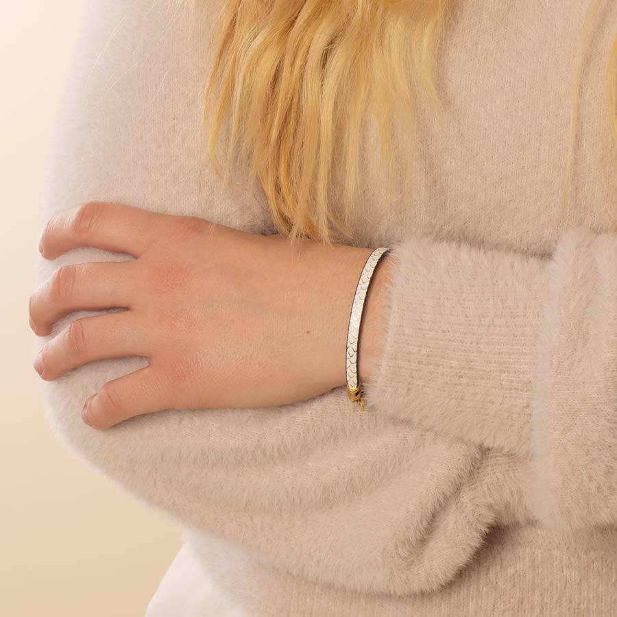 Woman wearing cream leather bracelet with textured scallop detail and gold flakes.