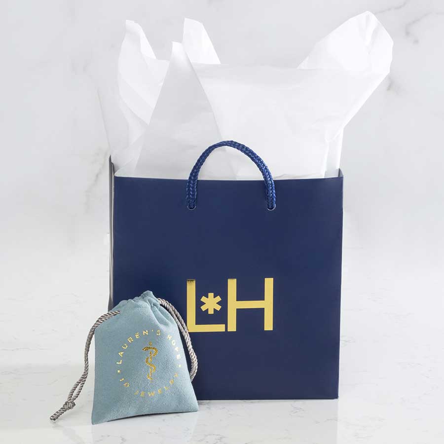 Navy blue gift bag with light blue suede jewelry pouch on marble background