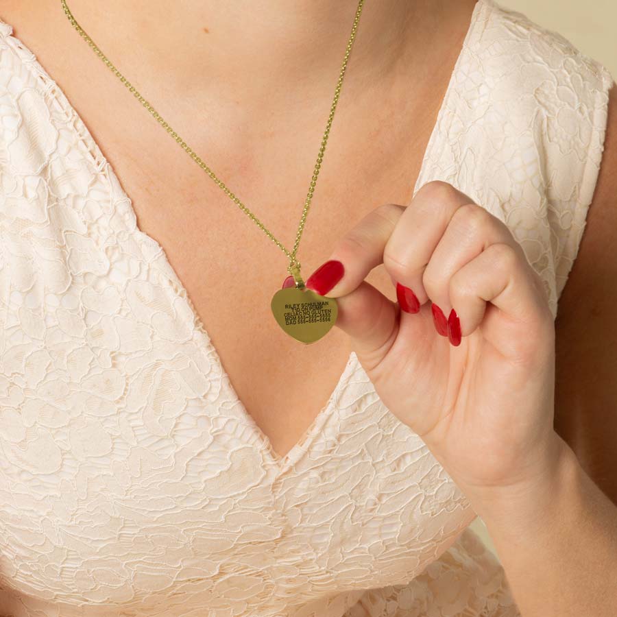 Woman showing custom laser engraved gold medical ID pendant necklace