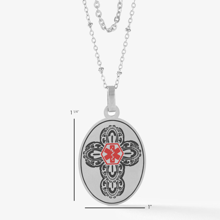 Scale of the 1-½” x 1” Oval Cross Medical ID Necklace, a tag with an intricate cross pattern and red caduceus in the center