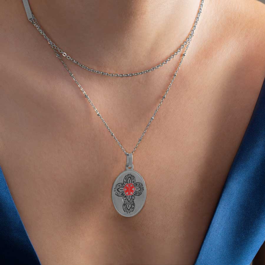 Woman in blue dress wearing medical alert necklace with decorative cross and red medical symbol