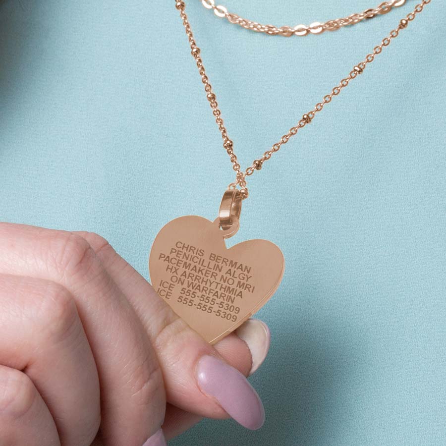 Woman showing premium laser engraving on rose gold tone heart pendant necklace.