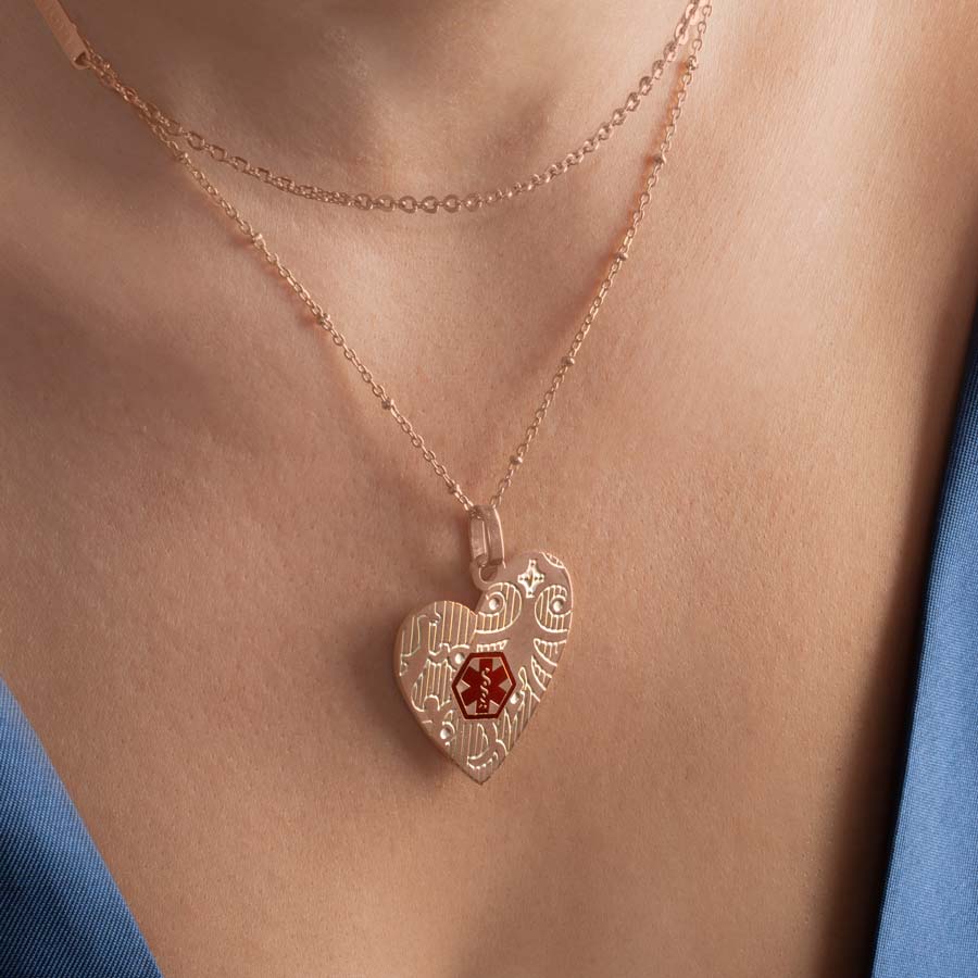 Woman wearing rose gold tone heart pendant on layered necklace chain.