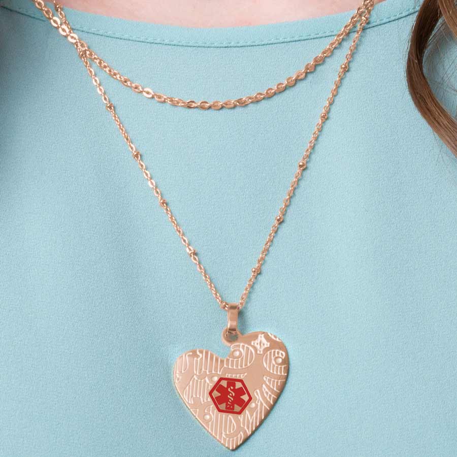 Woman wearing rose gold tone heart pendant on layered necklace chain.