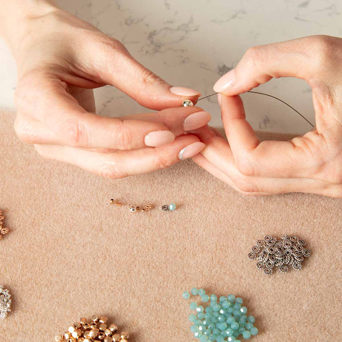 Hands stranding beads on wire for beaded medical ID bracelet